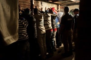 A group of men stand with their hands against the wall after the house where they were gambling was raided during a combined Metro Police and South African Police Services operation to arrest suspects, and search for drugs and firearms, in Manenburg, on August 27, 2013. Photo: AFP/Rodger Bosch