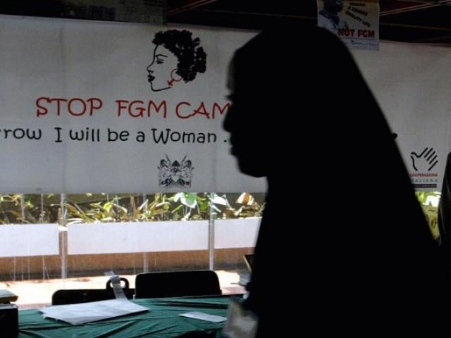 A young woman walks past a campaign banner against female genital mutilation at a 2004 international conference in Kenya to end the practice. Photo: AFP/SIMON MAINA
