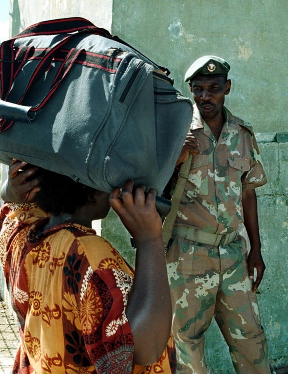 A South African soldier checks the passports of Zimbabwean citizens who walk across the Beit Bridge border post between the two countries to buy food in January 2003. Photo: AFP