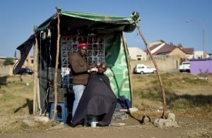 A street barber cuts the hair of a customer in his barber shop in the Diepkloof area of Soweto on June 30, 2013. Photo: AFP/Odd Anderson