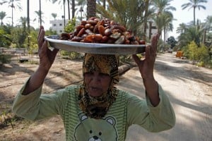 A Palestinian woman carries a pile of freshly harvested dates on her head. Photo: AFP/Said Khatib