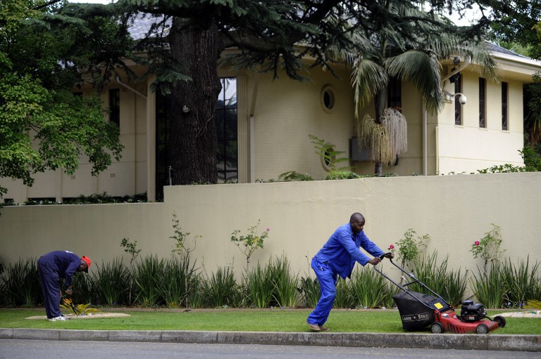 Gardners mow the grass outside the house of former South African president Nelson Mandela in Johannesburg in December 2012. Photo: AFP/ALEXANDER JOE
