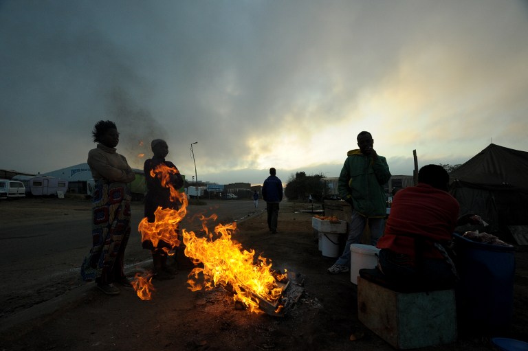 People gather around a fire to warm up in Alexandra township in Johannesburg. Photo: AFP/Alexander Joe