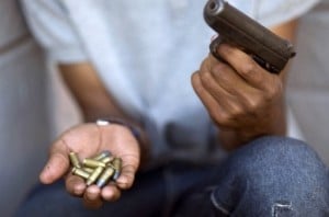 A young gang member in the Cape Flats shows a gun and ammunition, in November 2012. Gang murders are frequent in the district. Photo: AFP/Rodger Bosch