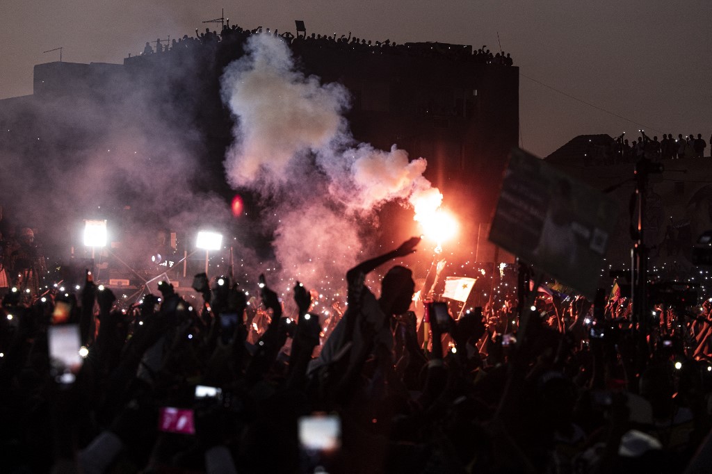Des partisans de l'opposition agitent des drapeaux sénégalais et des lumières sur leurs téléphones lors d'un meeting deux jours avant le procès de l'un des leaders, Ousmane Sonko, à Dakar, le 14 mars 2023. 