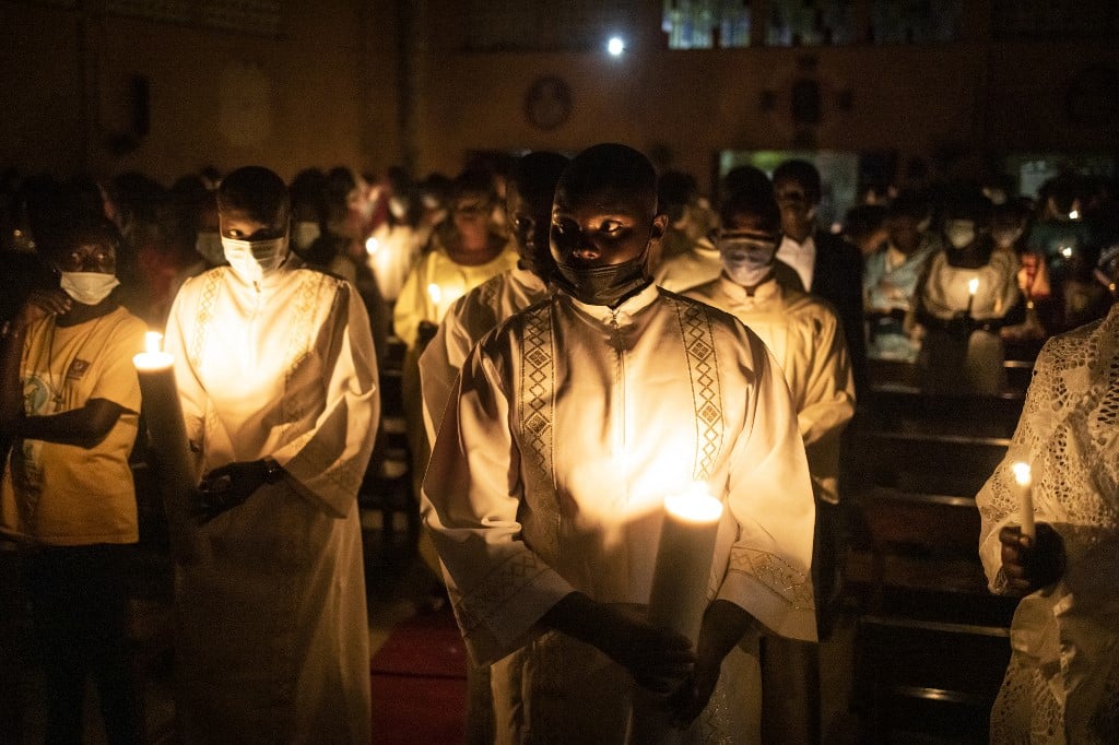Des enfants de chœur allument des cierges à l'entrée de l'église lors de la veillée pascale sur l'île de Fadiouth, au Sénégal, le 3 avril 2021. Le village de Fadiouth se trouve sur une île de coquillages et un pont piétonnier le relie à la partie continentale du Sénégal. Le Sénégal dans son ensemble est majoritairement musulman, mais l'île de Fadiouth est en majorité chrétienne. JOHN WESSELS / AFP