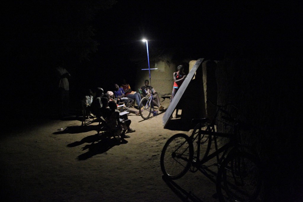Des élèves assistent à des cours du soir sous un lampadaire solaire mobile nommé par les habitants "Foroba Yelen", en langue bambara, dans le village de Sanogola (région de Ségou), au nord-est de Bamako, le 25 avril 2014. HABIBOU KOUYATE / AFP