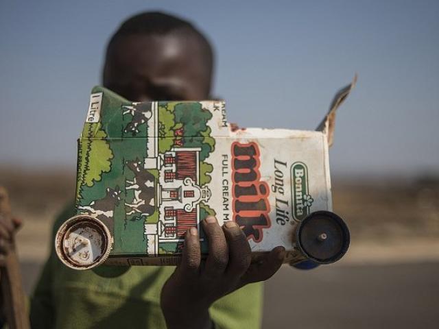 A child holds up a toy truck he made out of a milk carton in July 2015 in Simunye township, west of Johannesburg. Photo: AFP/MUJAHID SAFODIEN