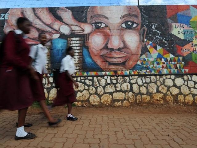 Girls walk past a mural created by “Kurema, Kureba, Kwiga” ("to create, to see, to learn") in October 2015 in Kigali. Photo: AFP/Tony Karumba