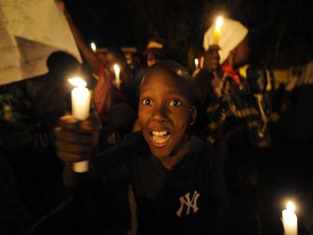 A young boy holds a candle as he takes part in a protest after dusk on September 11, 2015 at the Deep Sea Slum near the upmarket Westlands area of Kenya's capital Nairobi. Residents of the slum, facilitated by Amnesty international, are protesting di