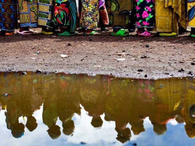 Pregnant women are reflected in a puddle as they stand in line to receive birth kits from a local NGO at a camp for internally displaced people in Kibati in the Democratic Republic of Congo in December 2008. Photo: AFP/YASUYOSHI CHIBA