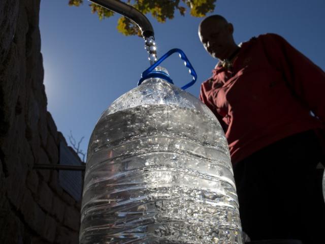 A man collects drinking water from taps that are fed by a spring in Newlands in May 2017 in Cape Town. Photo: AFP/Rodger Bosch