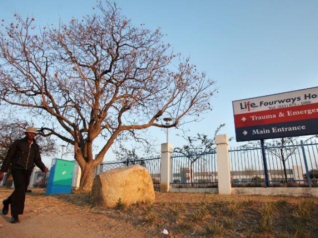 A man walks past a sign for a private hospital in Fourways, Johannesburg, in August 2011. Photo: AFP/PABALLO THEKISO