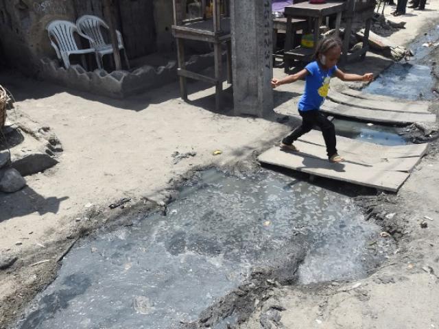 A young girl runs past a gutter filled with stagnant water during a malaria prevention action in a district of Lagos in April 2016. Photo: AFP/PIUS UTOMI EKPEI