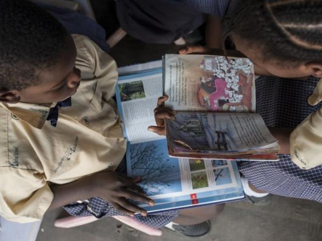A boy and a girl read books in a mobile library in Nigeria in January 2018. Photo: AFP/STEFAN HEUNIS