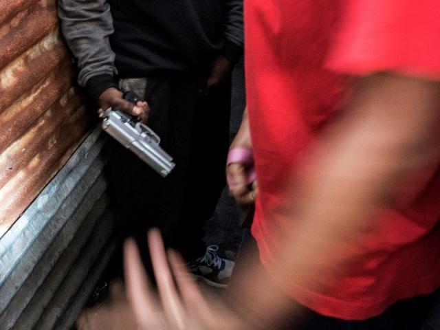 A young man passes a gun to another man in July 2016 in a Mongrels gang stronghold in Hanover Park, Cape Town. Photo: RODGER BOSCH/AFP