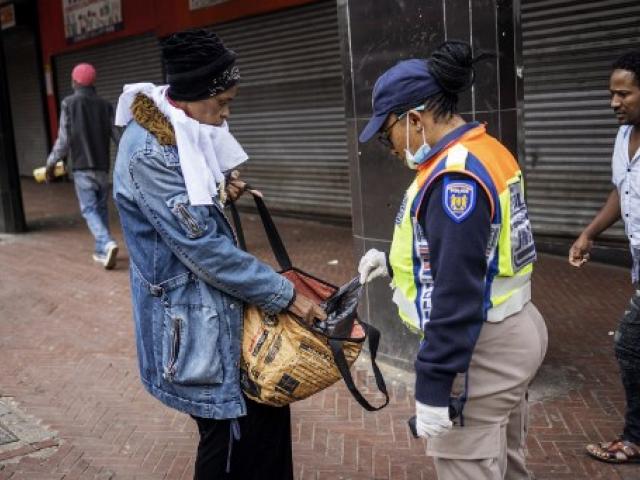 JMPD police woman inspecting a civilian's bag 