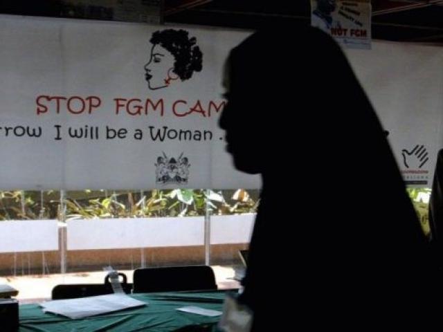 Une jeune femme passe devant une banderole de la campagne contre les mutilations génitales féminines lors d'une conférence internationale en 2004 au Kenya. Photo : AFP.