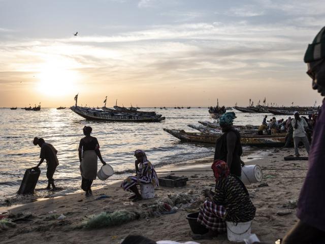 Des femmes attendent d'acheter du poisson sur les bateaux qui arrivent au port de pêche de Mbour, le 16 novembre 2020. Ces derniers mois, Mbour a été un site de départ populaire pour les migrants illégaux souhaitant atteindre l'Europe. JOHN WESSELS / AFP