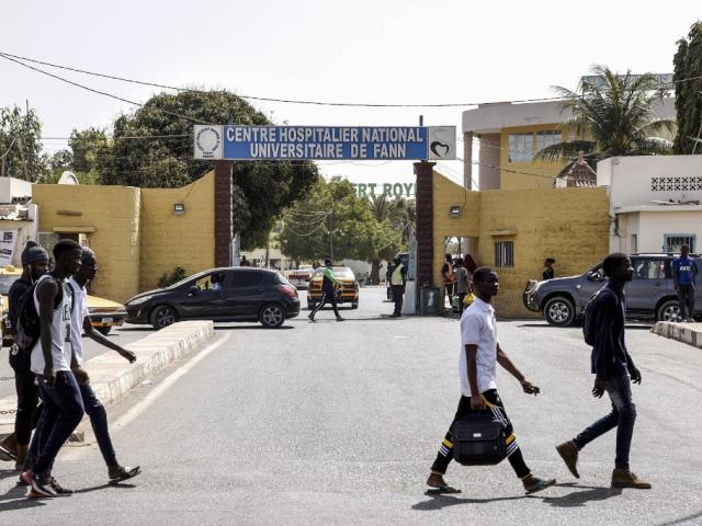 Des piétons passent devant l'entrée du Centre hospitalier national universitaire de Fann, à Dakar, le 2 mars 2020