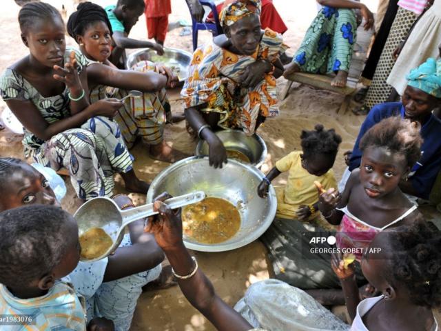 Des membres de plusieurs familles mangent un plat servi lors du repas de midi dans le village de Merine Dakhar, le 29 mai 2008. Le manque de précipitations et la sécheresse prolongée qui s'en est suivie sont responsables du faible rendement des cultures dans la région, ce qui a entraîné une augmentation de la pauvreté. Le village de 55 familles a vu six de ses jeunes se diriger vers la capitale Dakar et Mbour en raison du manque de nourriture. PHOTO AFP / GEORGES GOBET