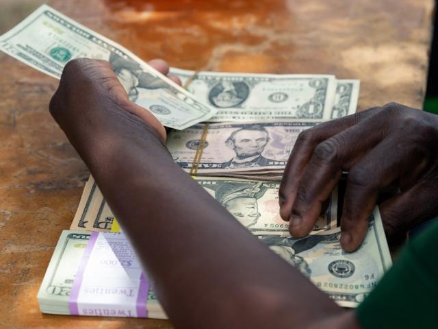 Un agent de sécurité compte des petites coupures d'argent en USD, le 14 mars 2019, dans la zone rurale de Mutoko au Zimbabwe. Jekesai NJIKIZANA / AFP