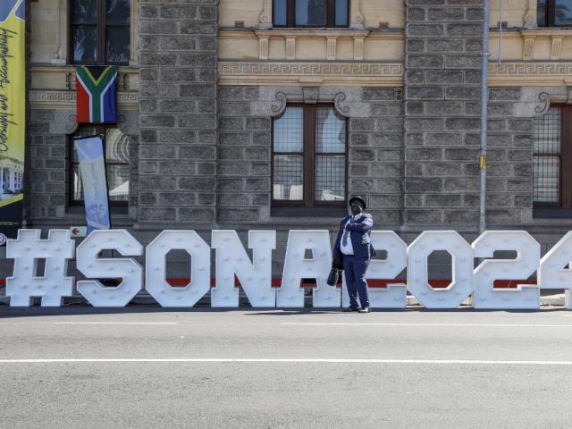A man walks past a sign outside Cape Town City Hall on 8 February 2024, ahead of South Africa's state of the nation address.