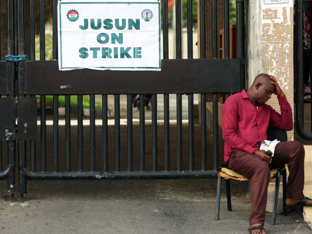 A gateman next to the banner of the National Labour Congress (NLC) at the gate of Nigeria's Federal High Court