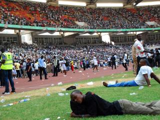 Job-seekers lie on the pitch after a stampede in Abuja National Stadium, where thousands of people came to apply for work at the Nigerian immigration department in March 2014. At least seven people were killed and dozens injured. Photo: AFP