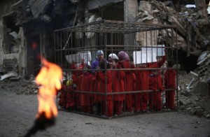 Here, a picture taken on February 15, 2015 by an AFP freelancer in Douma, outside Damascsus, shows a grisly stage-act organised by Syrian rebels to denounce the bombardment of the town by government forces and the international community's failure to act. Children dressed in orange stand in a cage, recalling the horrific fate of of the Jordanian pilot burned alive by the Islamic State group a few days earlier. Circulated without a clear enough caption, such an image is open to all manner of interpretations. Photo: AFP/ Abd Doumany